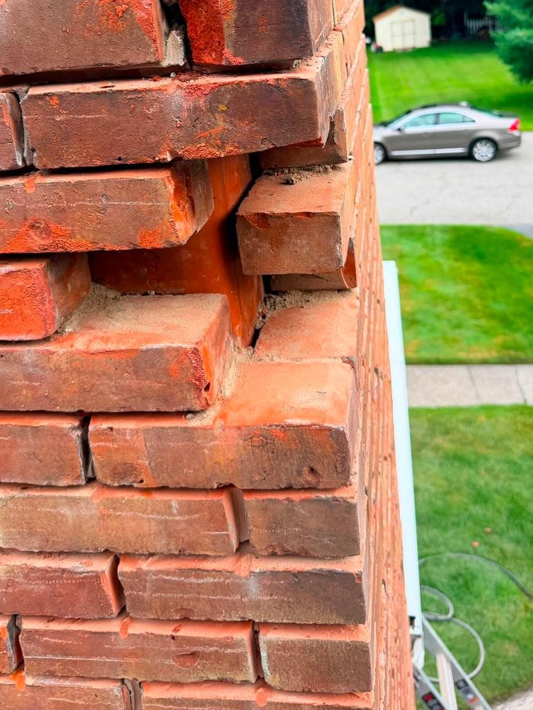 Spalling and crumbling brick on a chimney corner needing masonry repair