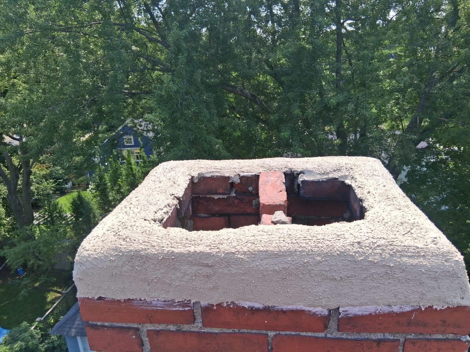 Freshly formed cement chimney crown sloped to shed water, mid-project, in Massachusetts